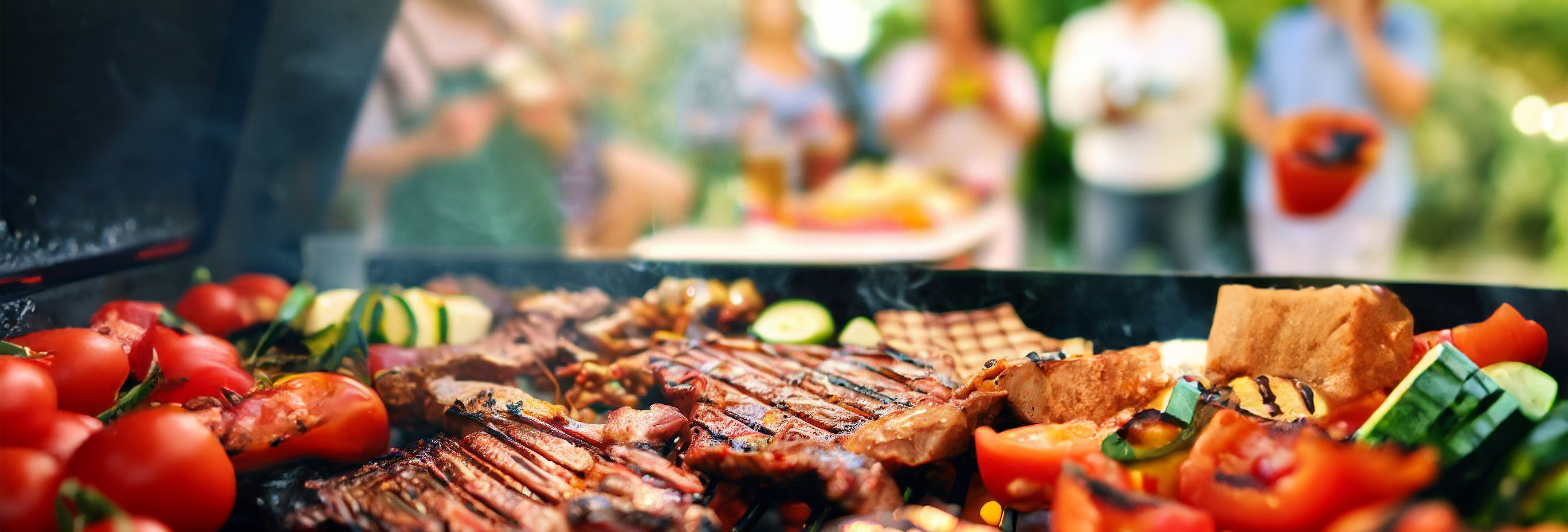 Close-up of food grilling on a BBQ with people in the background.